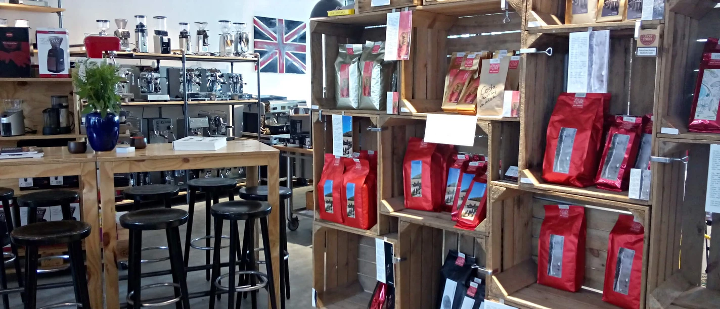 Een lichte koffieshop met schappen vol koffiezakken en aantrekkelijk meubilair.