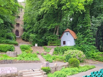 Freilichtbühne Nettelstedt Freilichtbühne umgeben von Wald, zwei steinerne Treppen führen zu einem historischen Turm und einem Häuschen.