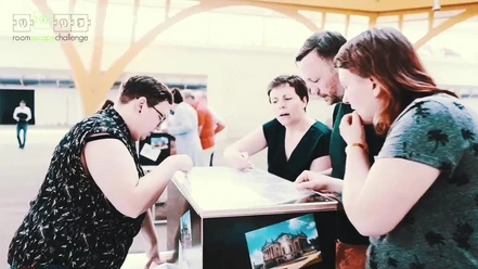 A group of people are gathered around a mobile puzzle box.