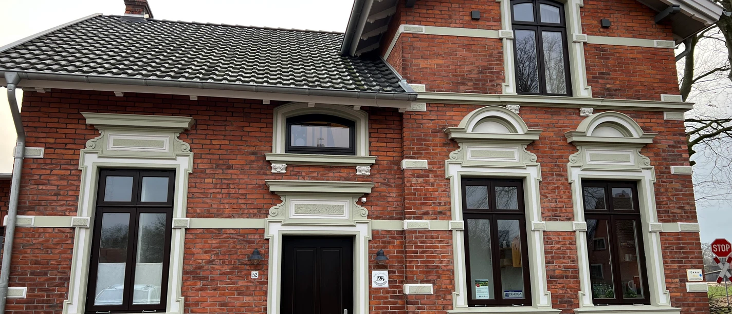 Villa Gleisbett Historische rote Backsteinvilla mit weißen Fensterrahmen und hölzernen Türen, umgeben von Bäumen.