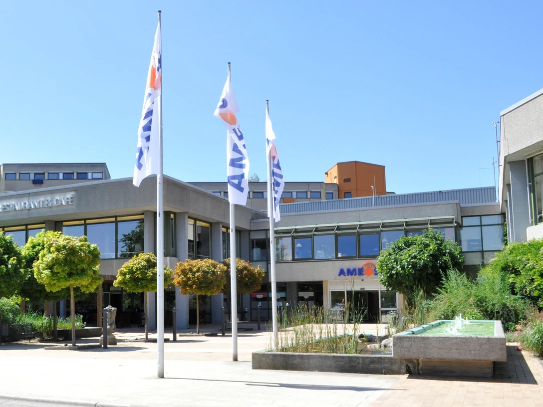 AMEOS_Eingang (©AMEOS Einrichtungen Ratzeburg).jpg Die Senioreneinrichtung von außen. Vor dem Eingang stehen Bäume und gehisste Fahnen mit der Aufschrift AMEOS