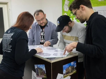 Mobile Rätselkiste - Freizeitaktivitäten in Leipzig Mehrere Menschen sind mit über eine Box gebeugt und sind mit dem lösen einer Rätselkiste beschäftigtSeveral people are bent over a box and are busy solving a puzzle boxNěkolik lidí je skloněno nad krabicí a zabývá se řešením hlavolamu.Kilka osób pochyla się nad pudełkiem i jest zajętych rozwiązywaniem łamigłówkiVerschillende mensen zitten gebogen over een doos en zijn bezig met het oplossen van een puzzeldoosDiverse persone sono chinate su una scatola e sono impegnate a risolvere un rompicapo.
