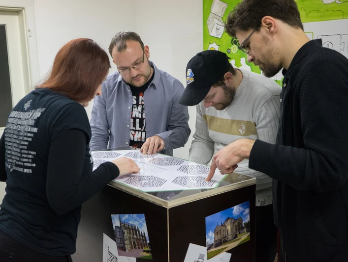 Mobile Rätselkiste - Freizeitaktivitäten in Leipzig Mehrere Menschen sind mit über eine Box gebeugt und sind mit dem lösen einer Rätselkiste beschäftigt