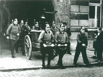 Feuerwehr vor Altem Rathaus Eine historische Aufnahme zeigt eine Gruppe von Feuerwehrmännern in traditioneller Uniform.