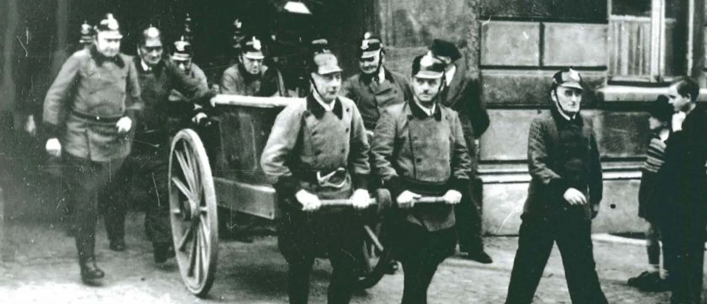 Feuerwehr vor Altem Rathaus Eine historische Aufnahme zeigt eine Gruppe von Feuerwehrmännern in traditioneller Uniform.