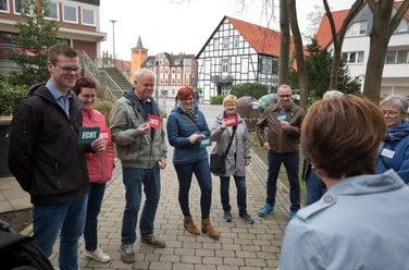 Lübbecke_Stadtführung_Echt oder Ente3_Oliver Krato.jpg Eine Gruppe von Menschen steht lächelnd im Freien und hält Schilder mit "Echt" oder "Ente".