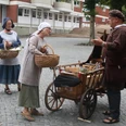 Lübbecke_Stadtführung_Marktgeschehen1_Lübbecke Marketing.JPG Drei Personen in historischer Kleidung beim Gespräch an einem Handwagen auf einem gepflasterten Platz.