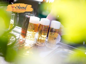 faf_prosit.jpg Vier Bierkrüge mit Schaumkrone stehen auf einem Tresen im Freien, Lichtstrahlen fallen darauf.