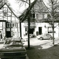Alte Lübbecker Bilder Historische Schwarz-Weiß-Aufnahme mit Fachwerkhäusern und klassischen Autos in einer beschaulichen Straßenszene.