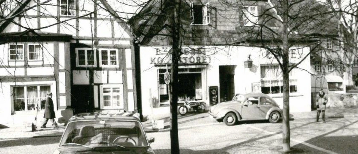 Alte Lübbecker Bilder Historische Schwarz-Weiß-Aufnahme mit Fachwerkhäusern und klassischen Autos in einer beschaulichen Straßenszene.