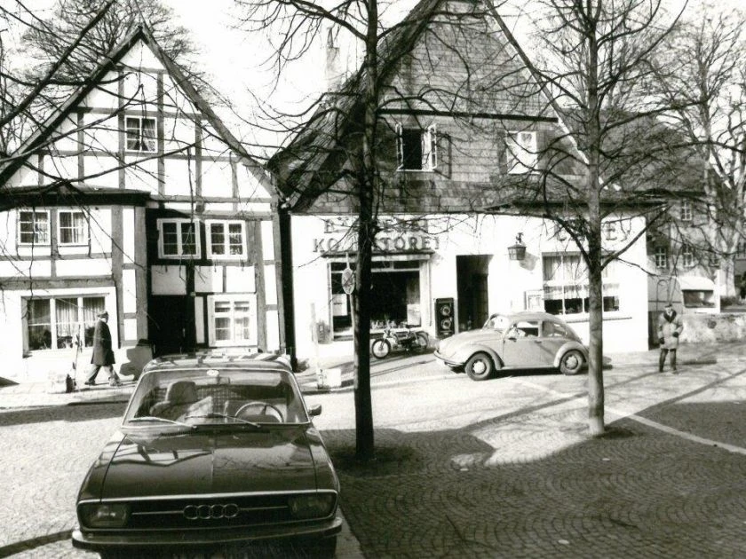 Alte Lübbecker Bilder Historische Schwarz-Weiß-Aufnahme mit Fachwerkhäusern und klassischen Autos in einer beschaulichen Straßenszene.