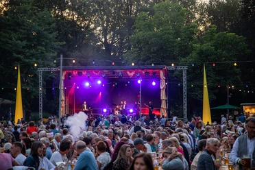 Parkfest-Kurpar-Wiese-Buehne-Menschen.jpg Menschen feiern vor großer Bühne beim Parkfest im Kurpark Bad Aibling