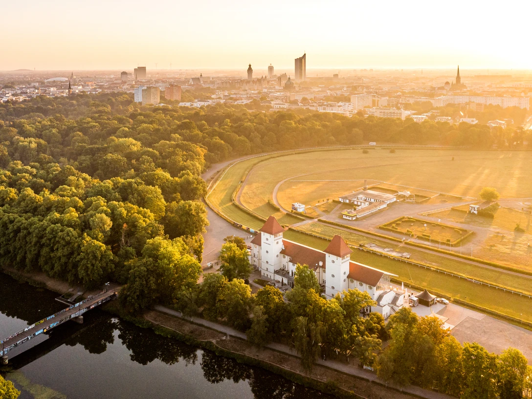 Rennbahn Scheibenholz mit Skyline - Grünes Leipzig Eine Luftaufnahme zeigt die Rennbahn Scheibenholz bei Sonnenaufgang undim Hintergrund die Leipziger Skyline