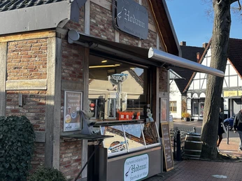 Aalräucherei Hodann Verkauf.jpeg Ein kleines Fachwerkgebäude beherbergt eine Aalräucherei mit Verkaufstheke unter blauem Himmel.