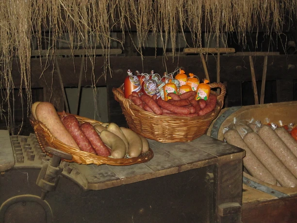 Wurstetag Museumshof Rahden Verschiedene Wurstsorten liegen in Körben in einem rustikalen Raum mit hängenden Getreidegarben.