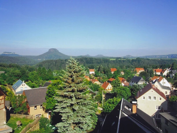 Blick auf eine kleine Stadt mit Häusern und einem großen Baum, Tafelberg im Hintergrund.