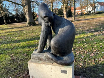 Raubkatze Bronzestatue einer Raubkatze mit nachdenklicher Haltung auf einem steinernen Sockel im Park.