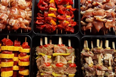 Angebot Landschlachthof Struppen Verschiedene Sorten von Fleischspießen in schwarzen Schalen, darunter Spieße mit Paprika, Mais und Tomaten, appetitlich angerichtet.