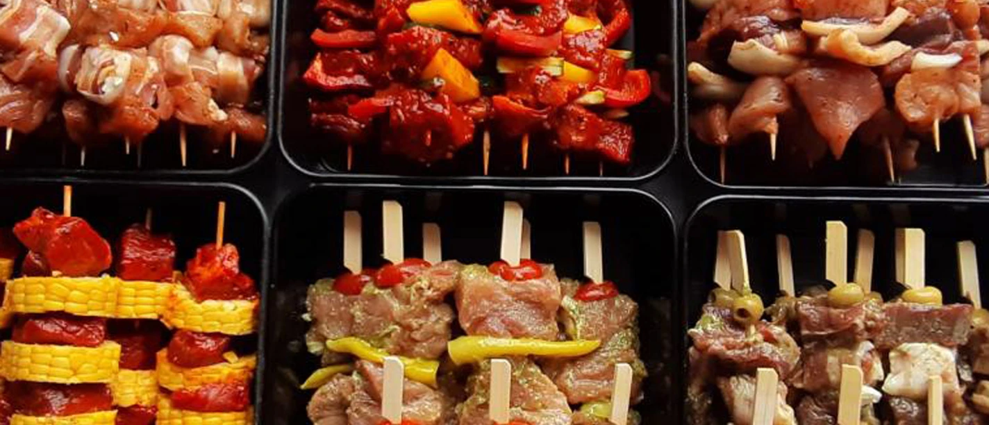 Angebot Landschlachthof Struppen Verschiedene Sorten von Fleischspießen in schwarzen Schalen, darunter Spieße mit Paprika, Mais und Tomaten, appetitlich angerichtet.