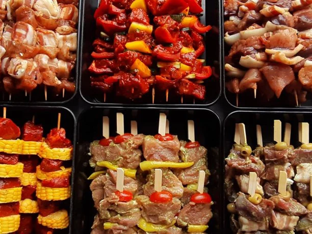 Angebot Landschlachthof Struppen Verschiedene Sorten von Fleischspießen in schwarzen Schalen, darunter Spieße mit Paprika, Mais und Tomaten, appetitlich angerichtet.