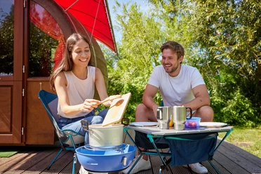 Camping im Wakenitz Camp in Rothenhusen Ein Paar kocht auf einem Campingplatz vor ihrer Unterkunft.