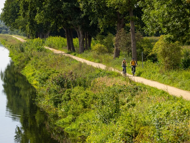 Paar fährt auf der Alten Salzstraße Fahrrad Ein Paar fährt auf der Alten Salzstraße Fahrrad. Auf der linken Seite ist der Elbe-Lübeck-Kanal zu sehen. Auf der rechten Seite der Fernradweg "Alte Salzstraße" und Bäume.