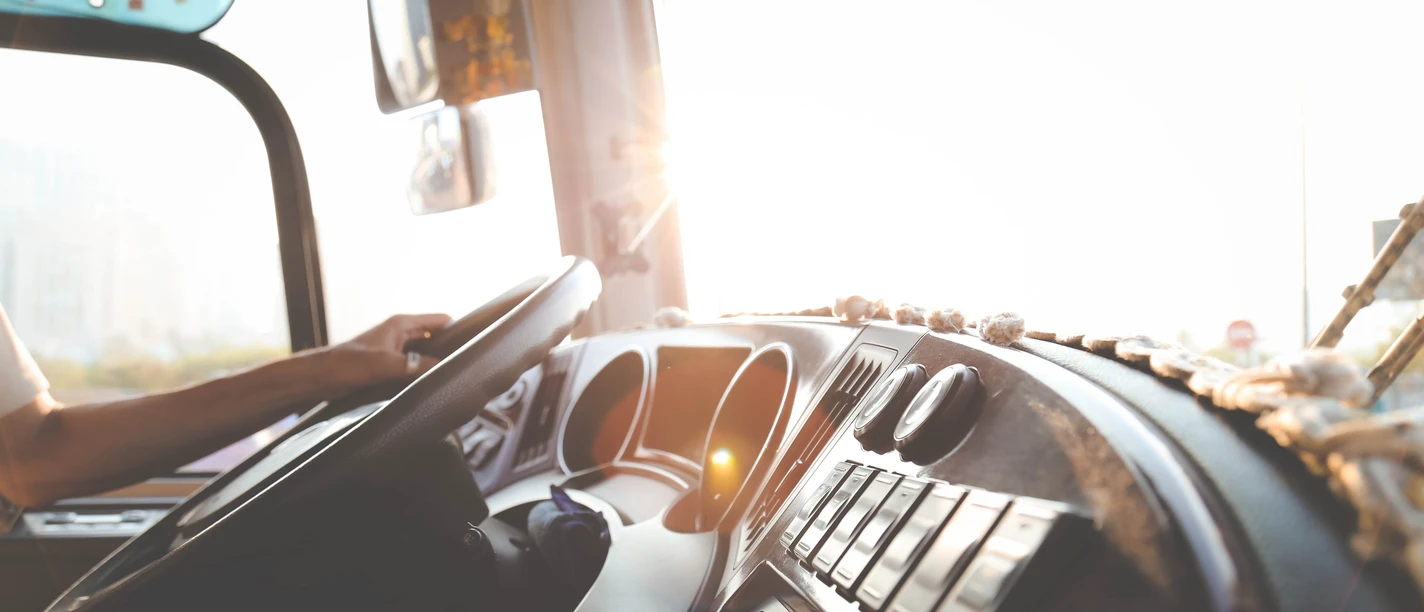 Panoramafahrt Blick auf das Lenkrad und Armaturenbrett eines Busses, mit Sonnenlicht, das von außen hereinfällt.