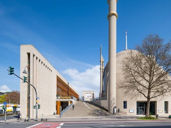Zentralmoschee Köln Im Vordergrund erhebt sich die Zentralmoschee Köln mit ihrer imposanten Fassade und Minaretten; links der moderne, rechtwinklige Vorbau.In the foreground is the Central Mosque of Cologne with its imposing façade and minarets; on the left is the modern, rectangular porch.