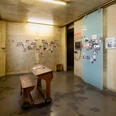 NS Dokumentationszentrum Ein heller Raum im NS-Dokumentationszentrum Köln. Historische Fotos schmücken blassgelbe Wände und eine Holzbank mit Pult bietet Platz zum Verweilen.