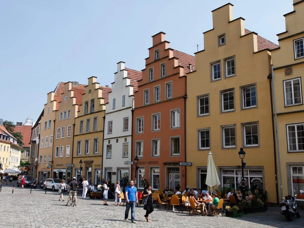 Giebelhäuser am Markt Osnabrück Historische Giebelhäuser in sanften Farben säumen den belebten Markt in Osnabrück bei Sonnenschein.