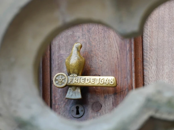 Deurgreep op het historische stadhuis van Osnabrück. Een gouden duif zit op een symbolische paal.