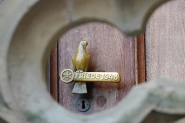 Door handle on the historic town hall of Osnabrück. A golden dove sits on a symbolic pole.