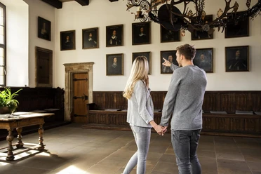 Een echtpaar bekijkt portretten in de historische Vredeszaal van het stadhuis van Osnabrück.