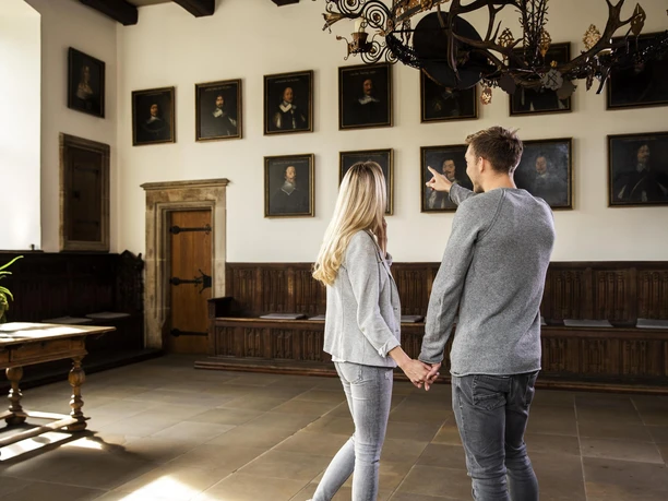 Een echtpaar bekijkt portretten in de historische Vredeszaal van het stadhuis van Osnabrück.