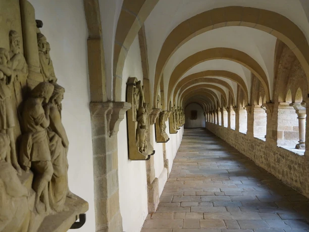Kreuzgang im Dom St. Petrus Gewölbter Kreuzgang im Dom St. Petrus Osnabrück mit Skulpturen entlang der Wände und gepflastertem Boden.