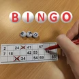 Bingo Hand markiert Zahlen auf einer Bingo-Karte; drei Kugeln mit 25, 30 und 73 vor rotem Stift.