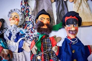 Punch and Judy Puppets from the Max Jacob Theatre Three colorful hand puppets with cheerful faces, in traditional costumes, lying on a table.