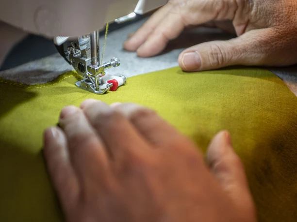 Stoff und Knopf Sabine Ritter Nähmaschine näht gelben Stoff; Hände führen ihn präzise.