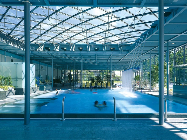 Geibeltbad Pirna Geibeltbad Pirna: Modernes Hallenbad mit Glasdach, blauem Wasser und mehreren schwimmenden Personen; helle, luftige Atmosphäre mit Pflanzen und Liegestühlen.