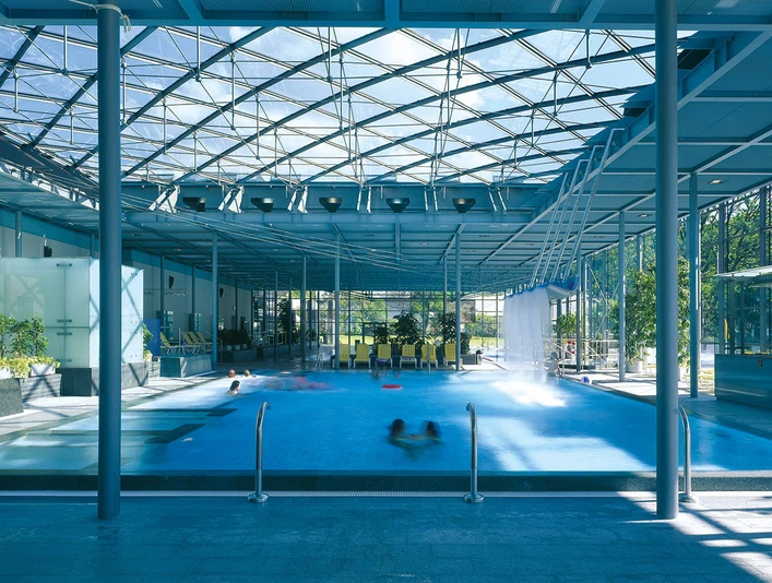 Geibeltbad Pirna Geibeltbad Pirna: Modernes Hallenbad mit Glasdach, blauem Wasser und mehreren schwimmenden Personen; helle, luftige Atmosphäre mit Pflanzen und Liegestühlen.