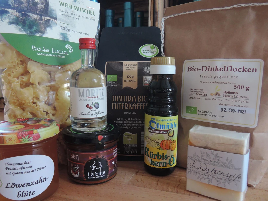 Hausgemachte Fruchtaufstriche Verschiedene regionale Produkte auf einem Tisch: Nudeln, Bio-Dinkelflocken, Filterkaffee, Kürbiskernöl, Fruchtaufstrich, BBQ-Sauce, Likör und handgesiedete Seife.