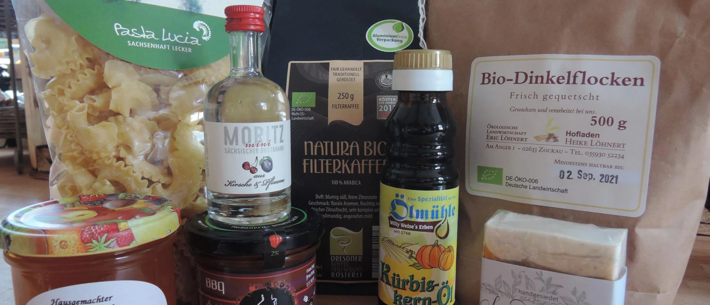 Hausgemachte Fruchtaufstriche Verschiedene regionale Produkte auf einem Tisch: Nudeln, Bio-Dinkelflocken, Filterkaffee, Kürbiskernöl, Fruchtaufstrich, BBQ-Sauce, Likör und handgesiedete Seife.