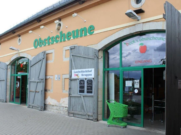 Obstscheune-Krietzschwitz-2.jpg Eingang einer Obstscheune mit grünen Türen und einem grünen Einkaufswagen, daneben ein Schild "Landschlachthof Struppen".
