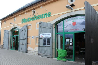 Obstscheune Krietzschwitz Eingang einer Obstscheune mit grünen Türen und einem grünen Einkaufswagen, daneben ein Schild "Landschlachthof Struppen".
