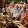 bispingen-spanferkel-4395.jpg Menschen servieren und teilen Spanferkel bei einem traditionellen Dorffest auf dem Grillplatz in Volkwardingen.
