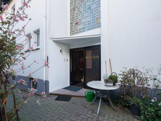 Ein einladender Eingang zu einem Gebäude mit einem Glasfenster. Ränder sind von Pflanzen und Blumen umgeben.