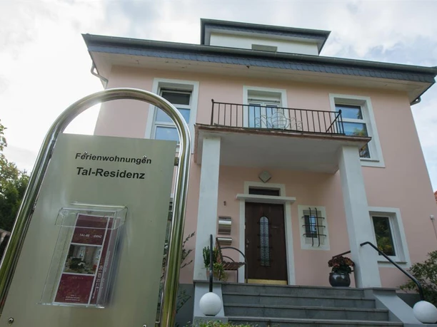 Ein schönes Ferienhaus mit einem einladenden Eingang. Die Fassade ist in sanften Farben gehalten und bietet einen Balkon.