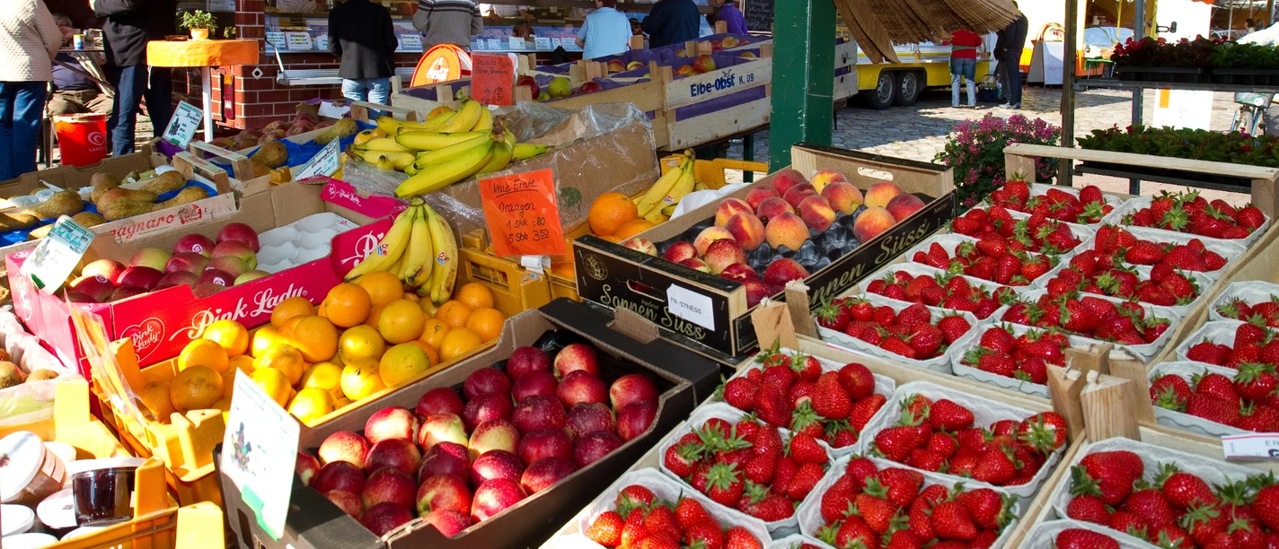 Wochenmarkt vor dem Rathaus.jpg Blick vom Inneren eines Wochenmarktstandes auf frisches Obst.