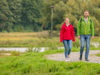 <p>Ein lächelndes Paar wandert auf einem grünen Pfad in herrlicher Natur.</p>