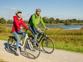 Delbrueck-Steinhorster Becken-Teutoburger-Wald-Tourismus-D-Ketz-074.jpg Zwei Radfahrer genießen eine Fahrt auf einem Schotterweg durch eine idyllische Landschaft mit Fluss.